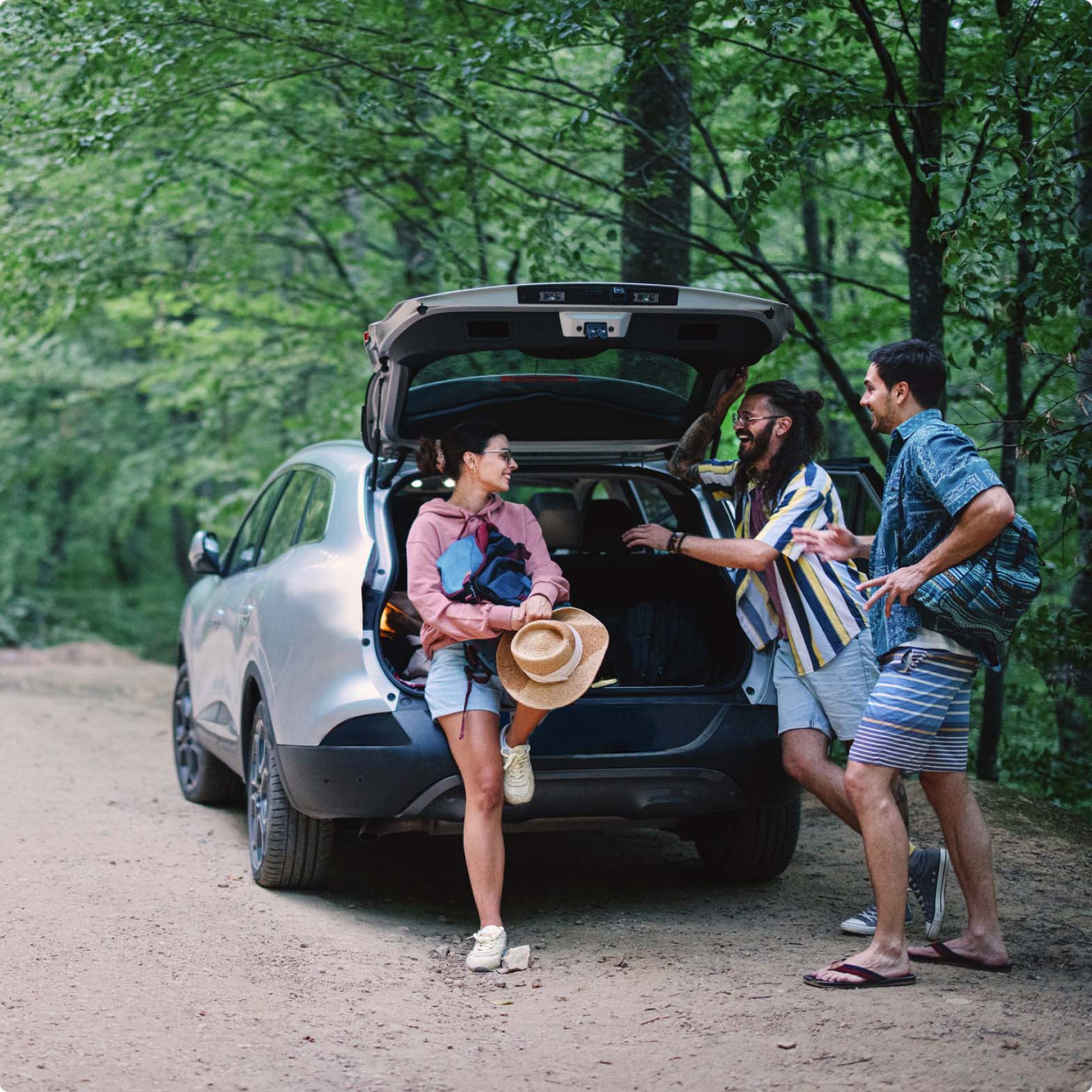 A group of friends talking stood next to the open boot of their car A group of friends talking stood next to the open boot of their car
