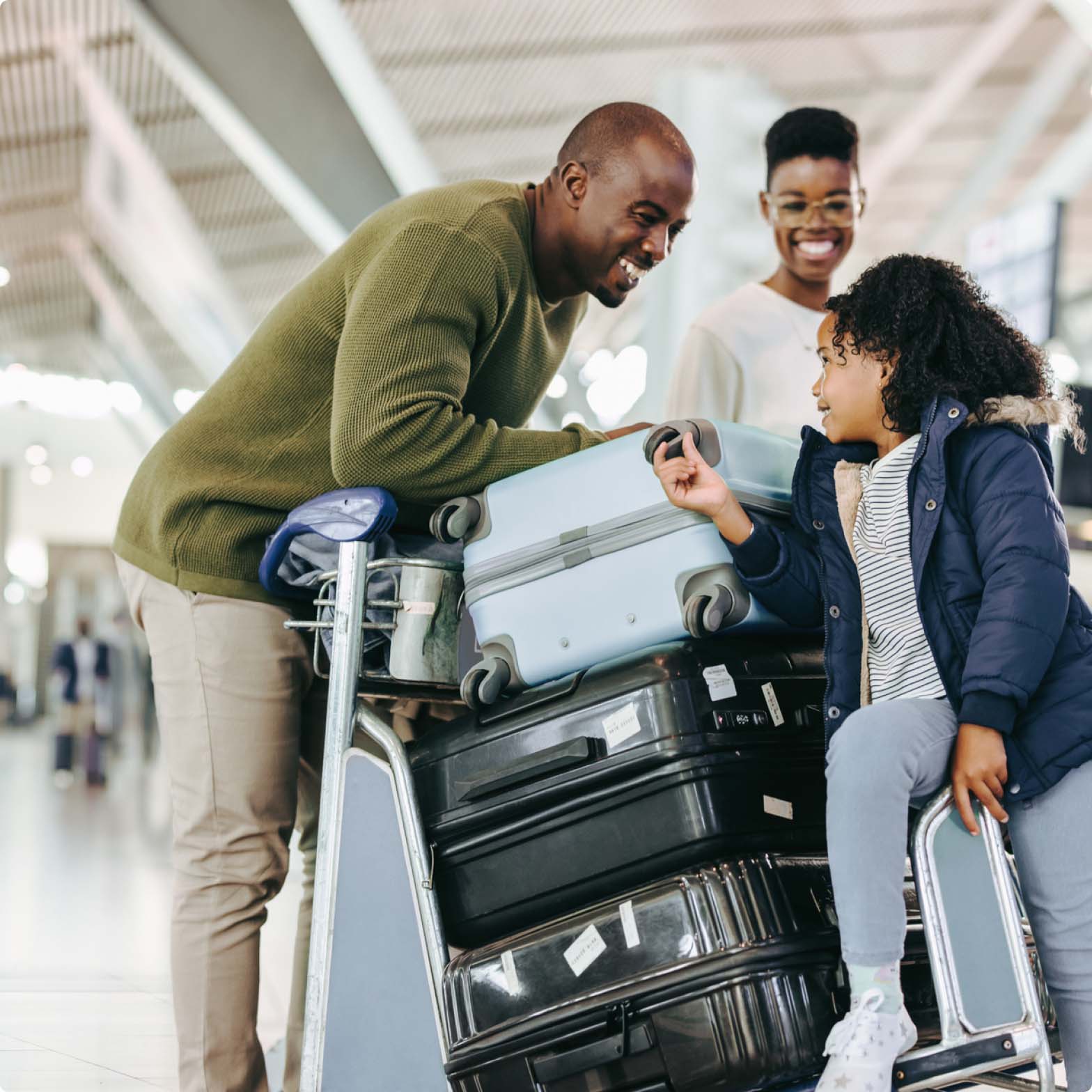 A family laughing while pushing luggage through the airport A family laughing while pushing luggage through the airport