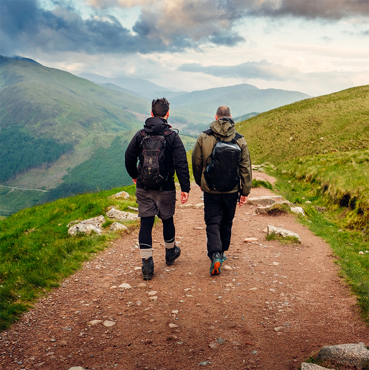 2 men pictured from the rear, walking along a hiking path on Ben Nevis in Scotland. 2 men pictured from the rear, walking along a hiking path on Ben Nevis in Scotland.