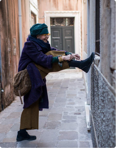 An older woman ties her shoe in an alley way